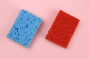 Bulaşıklar için renkli süngerler ya da pembe arka planda ev temizliği