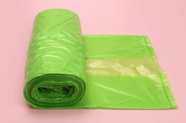 Pembe arka planda plastik yeşil çöp torbaları