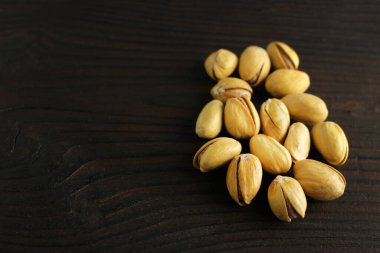 Siyah ahşap arka planda kabuklu çam fıstığı.