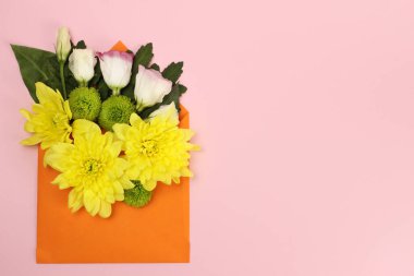 Sarı, yeşil Santini kasımpatı ve güllerin karışımı pembe arka planda bir zarf içinde