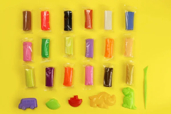 colorful clay, plasticine with tools on a yellow background