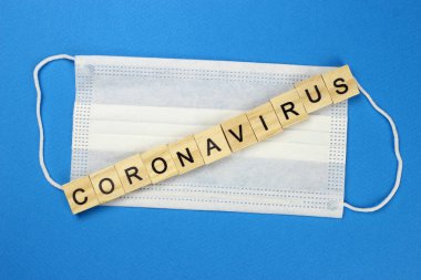 Korunaklı tıbbi maske takan tahtadan harflerle yazılmış koronavirüs. Tehlikeli 2019-NCov gribi enfeksiyonu