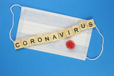 Korunaklı tıbbi maske takan tahtadan harflerle yazılmış koronavirüs. Tehlikeli 2019-NCov gribi enfeksiyonu