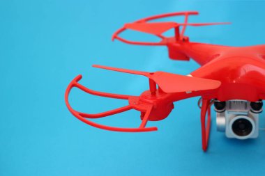 Drone, mavi arka planda kamerası olan bir kuadrokopter.