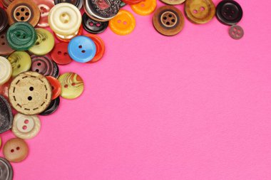 Pembe arkaplanda çeşitli boyutlarda, şekillerde ve renklerde düğmeler dikiliyor, boşluğu kopyala