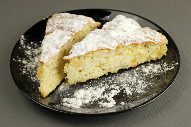 Lezzetli elmalı turta, Charlotte siyah bir arka planda siyah bir tabağa pudra şekeri serpiştirilmiş. Yan görünümü kapat.