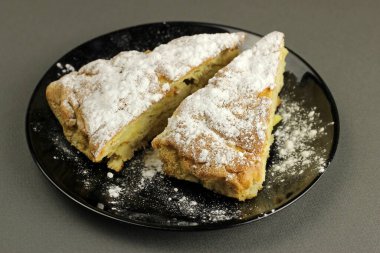 Lezzetli elmalı turta, Charlotte siyah bir arka planda siyah bir tabağa pudra şekeri serpiştirilmiş. Üst görünüm