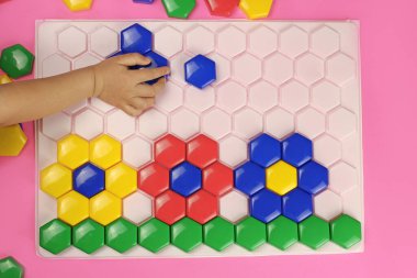 Bir çocuk renk bulmacası olan mozaikten çiçek toplar.