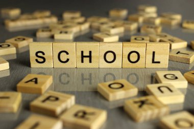 Kelime okulu gri bir arka planda kare tahta harflerden oluşur.