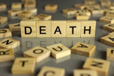 Ölüm kelimesi, gri bir arka planda kare ahşap harflerden yapılmış.