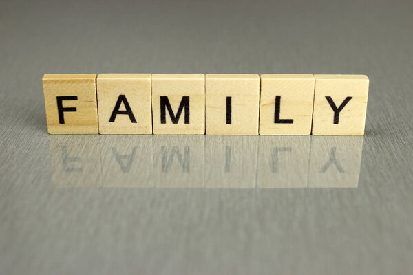 The word family is made up of square wooden letters on a gray background