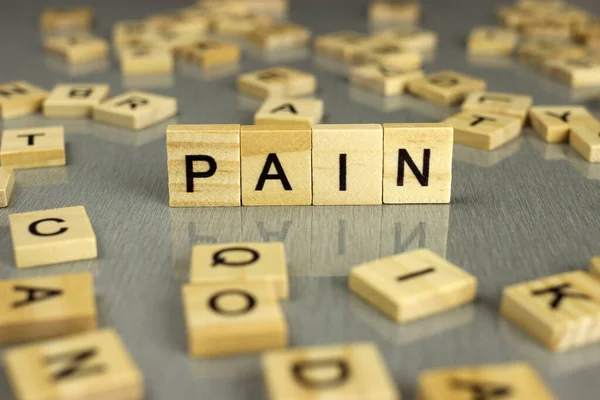 Das Wort Schmerz Besteht Aus Quadratischen Holzbuchstaben Auf Grauem Hintergrund — Stockfoto