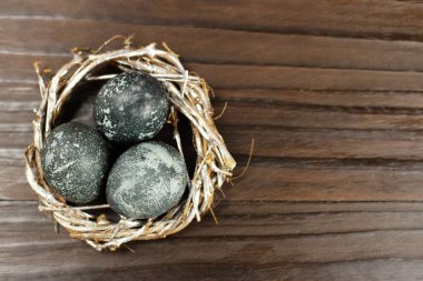 Ahşap arka planda bir yuvada menekşe Paskalya yumurtaları