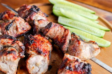 Lezzetli domuz kebabı, şiş kebap, salatalıklı tahta kesim tahtasına yakın şiş.