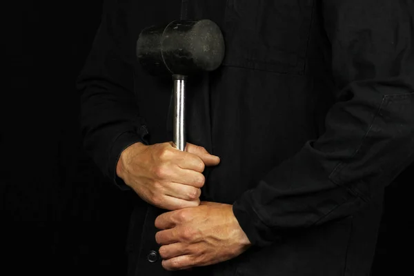 Rubber mallet in the hands of a worker on a black background