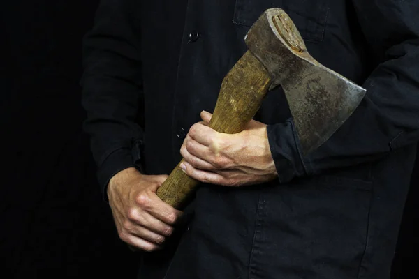 Axe in male hands in work clothes on a black background