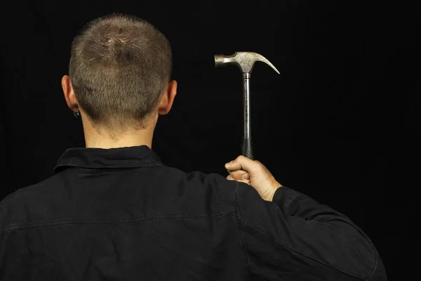 A man holds a hammer near his head