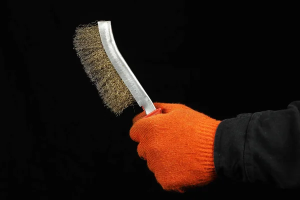 metal brush in the hand of a worker on a black background