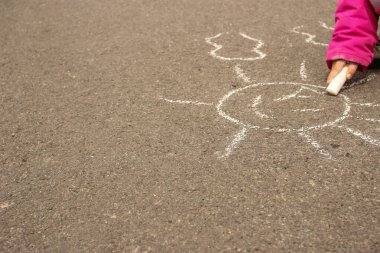 Çocuk kaldırıma tebeşirle güneşi çizer. Metnin için boşluk kopyala