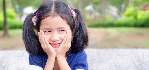 Aranyos ázsiai kislány ül a mosoly és a kezét az álla — Stock Fotó