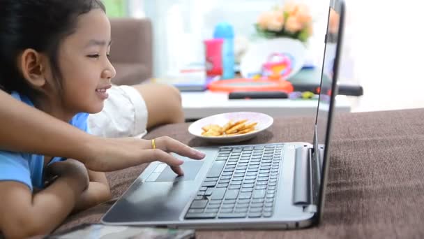 Gros plan de asiatique petite fille en utilisant ordinateur portable et casque à la maison — Video