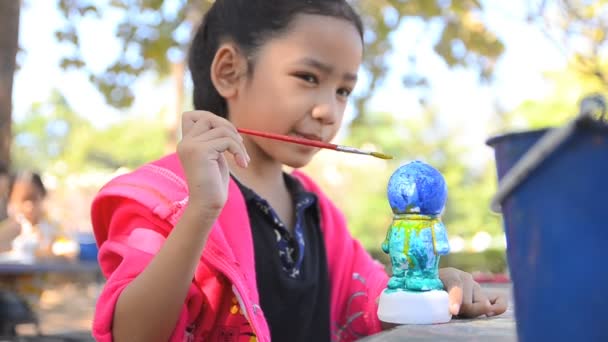 HD z bliska strzał Azjatki Mały dziewczyna malowania kolor wody na lalka — Wideo stockowe