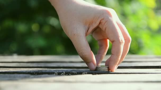 Hand van vrouw stapelen munten over natuur groene blad achtergrond — Stockvideo