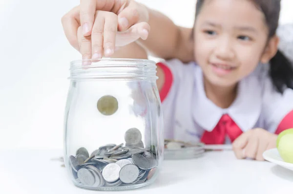 Asian little girl in Thai student uniform putting coin to glass — Stock Photo, Image