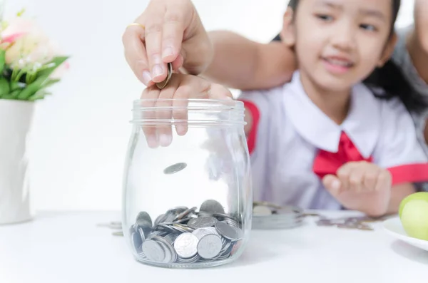 Asiatique petite fille en thaï étudiant uniforme putting coin to glass — Photo