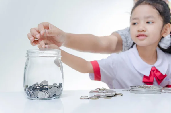 Asian little girl in Thai student uniform putting coin to glass — Stock Photo, Image