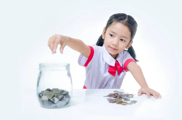 Азиатская маленькая девочка в тайской студенческой форме выкладывает монету в стекло — стоковое фото