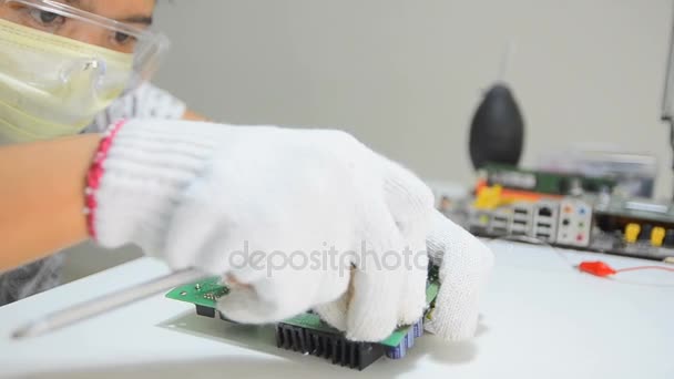 Technician is using screwdriver to loosen bolt screw to remove heat sink from electronic print circuit board — Stock Video