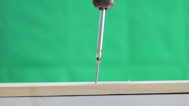 Manos del hombre usando taladro eléctrico para girar el tornillo a la madera sobre fondo verde — Vídeos de Stock