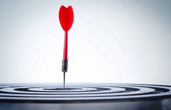 Close up shot red dart arrow on center of dartboard