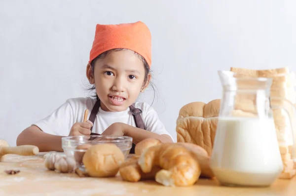 Retrato de niña asiática sosteniendo la masa en la mano y panadería o — Foto de Stock