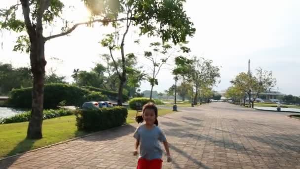 Asijská holčička běží ve veřejném parku s následovníkem fotoaparátu — Stock video
