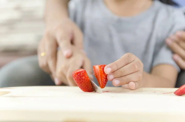 Asiatique petite fille coupe straberry sur planche à découper en bois avec — Photo