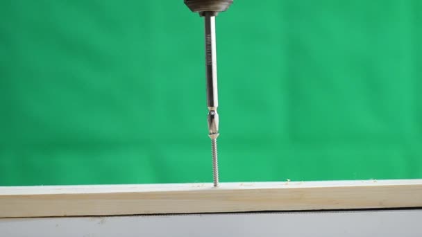 Електричний дриль, що обертається для затягування гвинта до дерева на зеленому фоні — стокове відео