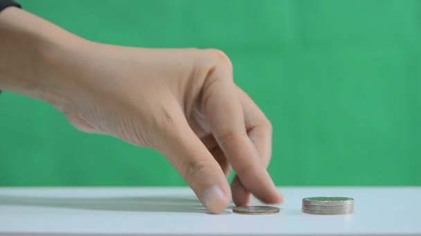 Bliska strzał ręka kobiety układanie monet na zielonym tle — Wideo stockowe