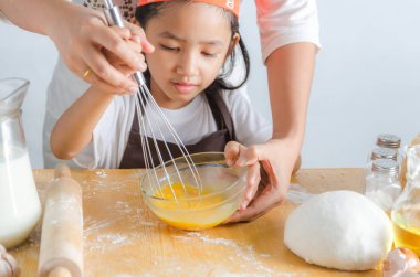 Asyalı küçük kız paslanmaz çelik çırpıcı yumurta karışımı olarak kullanmak 