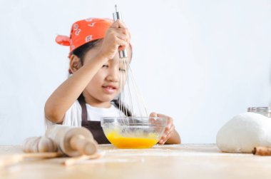 Asyalı küçük kız için yumurta karıştırmak için paslanmaz çelik çırpıcı kullanarak