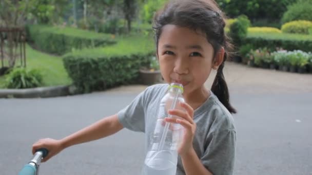 Leuke Aziatische little girl drinkwater in park met geluk en glimlach — Stockvideo