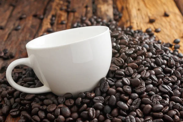 Primer plano de taza de cerámica blanca en la pila de café tostado oscuro — Foto de Stock