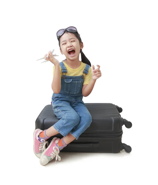 Asian little girl holds a plane in her hand and sits on her lugg — Stock Photo, Image