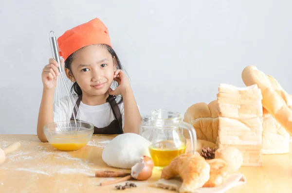 Asian little girl using stainless steel whisk to mix the egg for — Stock Photo, Image