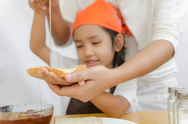 Asiática niña sostener el pan y miel dipper palo con mot — Foto de Stock