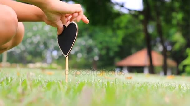 Manos de niño de pie corazón letrero de madera en vidrio verde — Vídeos de Stock