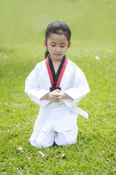 Asia kecil duduk di rumput hijau menutup matanya dengan co — Stok Foto