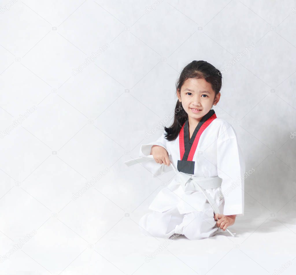 Happy Asian little girl smile sitting and tie a white line in ta