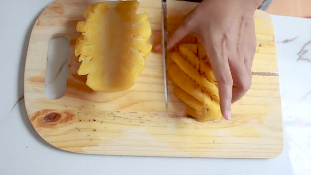Nära upp skott händerna på kvinnor som använder kökskniv att skära ananas kort skärpedjup — Stockvideo